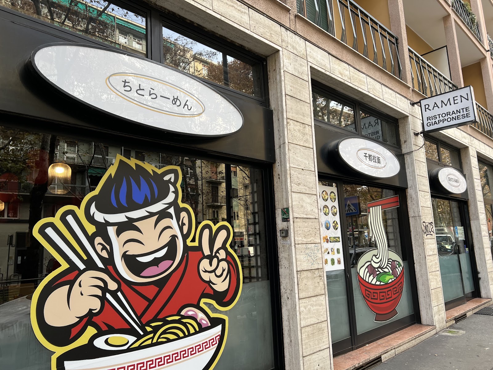 Facciata di Sento Ramen in Via Cenisio a Milano, con la mascotte disegnata in stile manga in vetrina